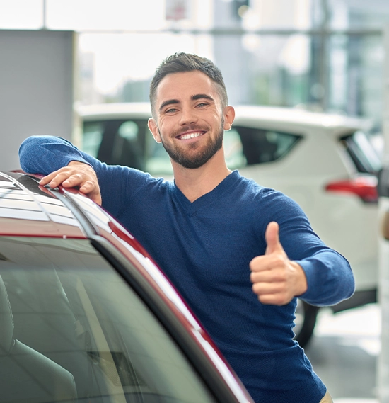 Brunette guy leaning on car and holding his right hand on top of it