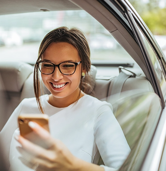 Young successful woman using smart phone in the car