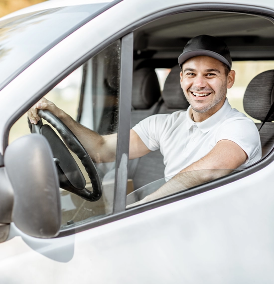 A cheerful driver is looking out the window of a white cargo van vehicle