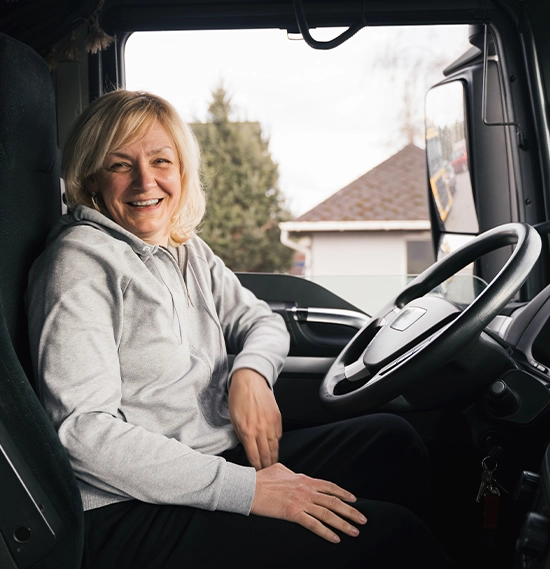 A smiling caucasian middle-aged woman inside a commercial vehicle
