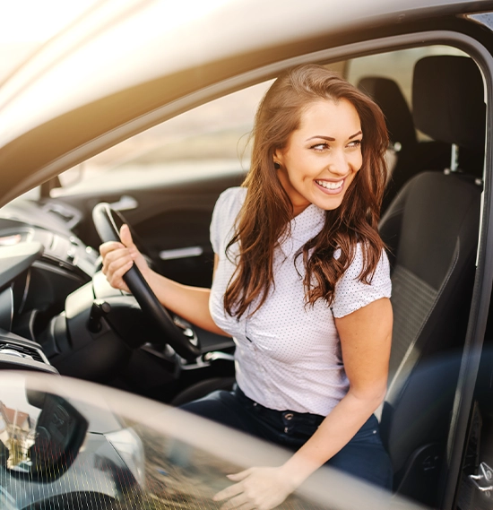 Caucasian woman with brown hair and toothy smile getting out of car