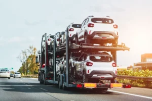 New cars on a hydraulic trailer are ready for delivery and sale. A car transporter truck carries many cars on a two-level modular ramp.