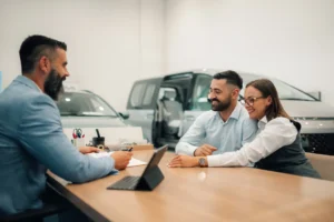 Couple discussing car financing and interest rates with a salesperson at a dealership showroom.